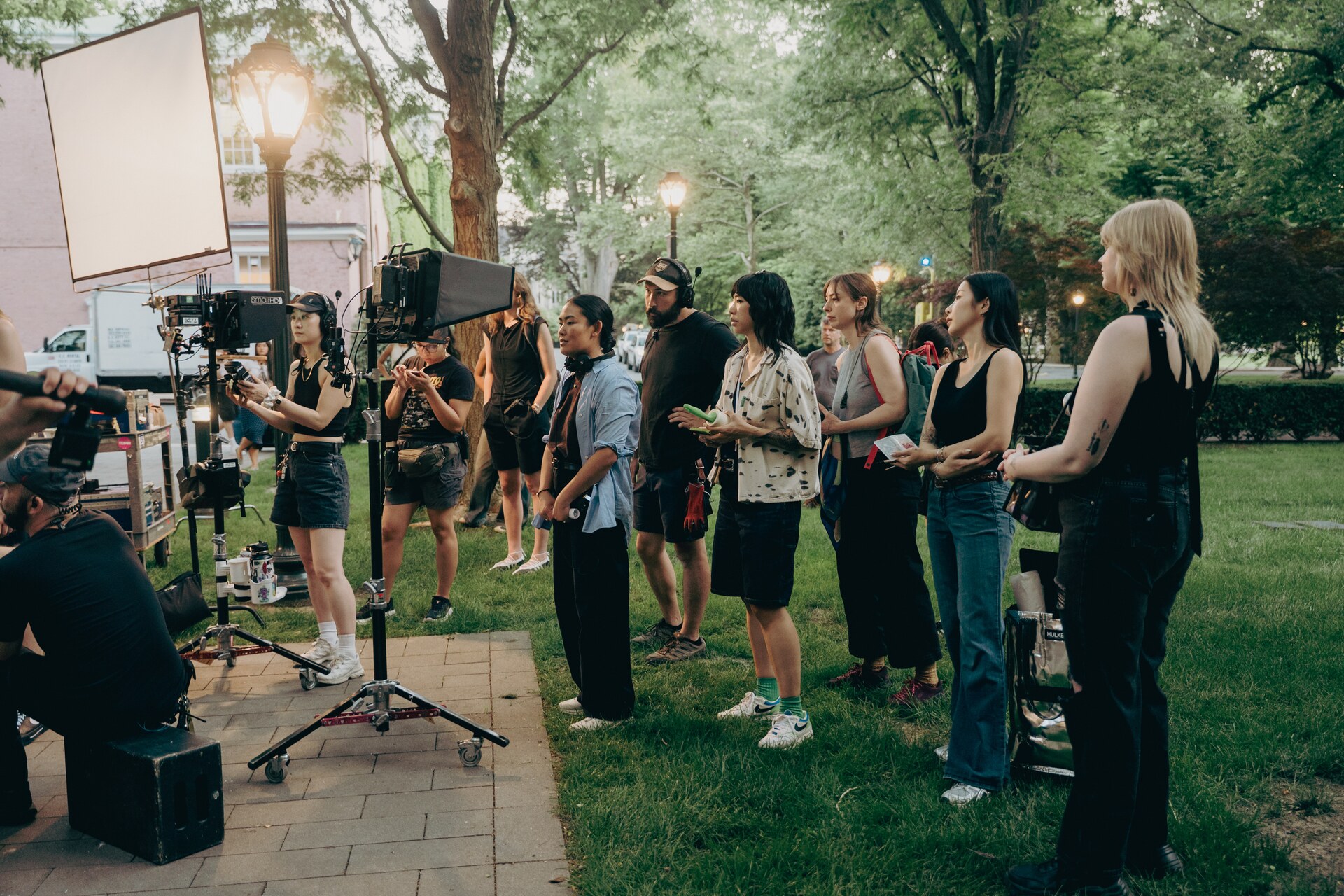Book Talk cast and crew gathered beside lights and a cinema camera outdoors.
