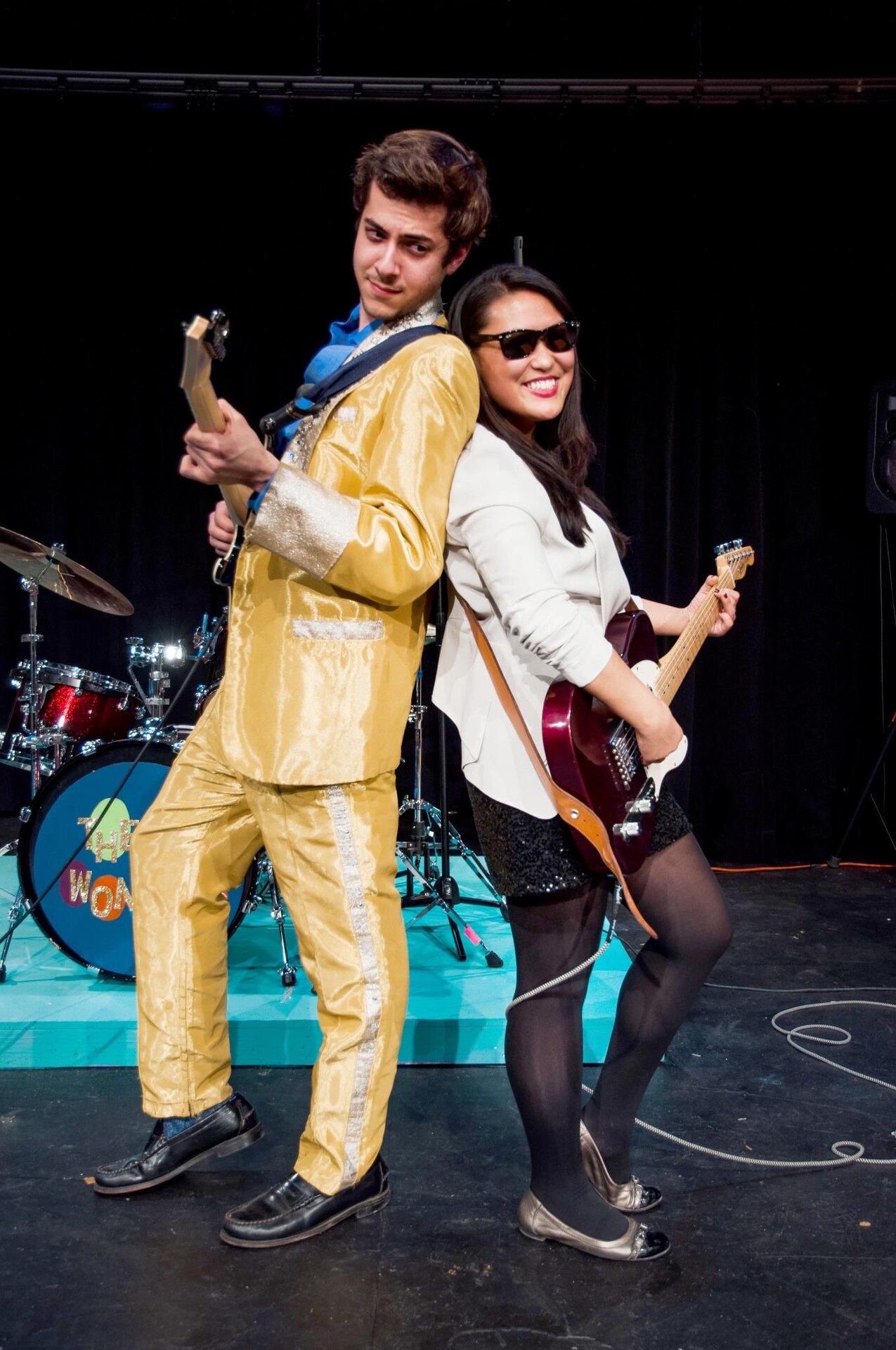 Two performers dancing in front of The Wonders band during the stage production.