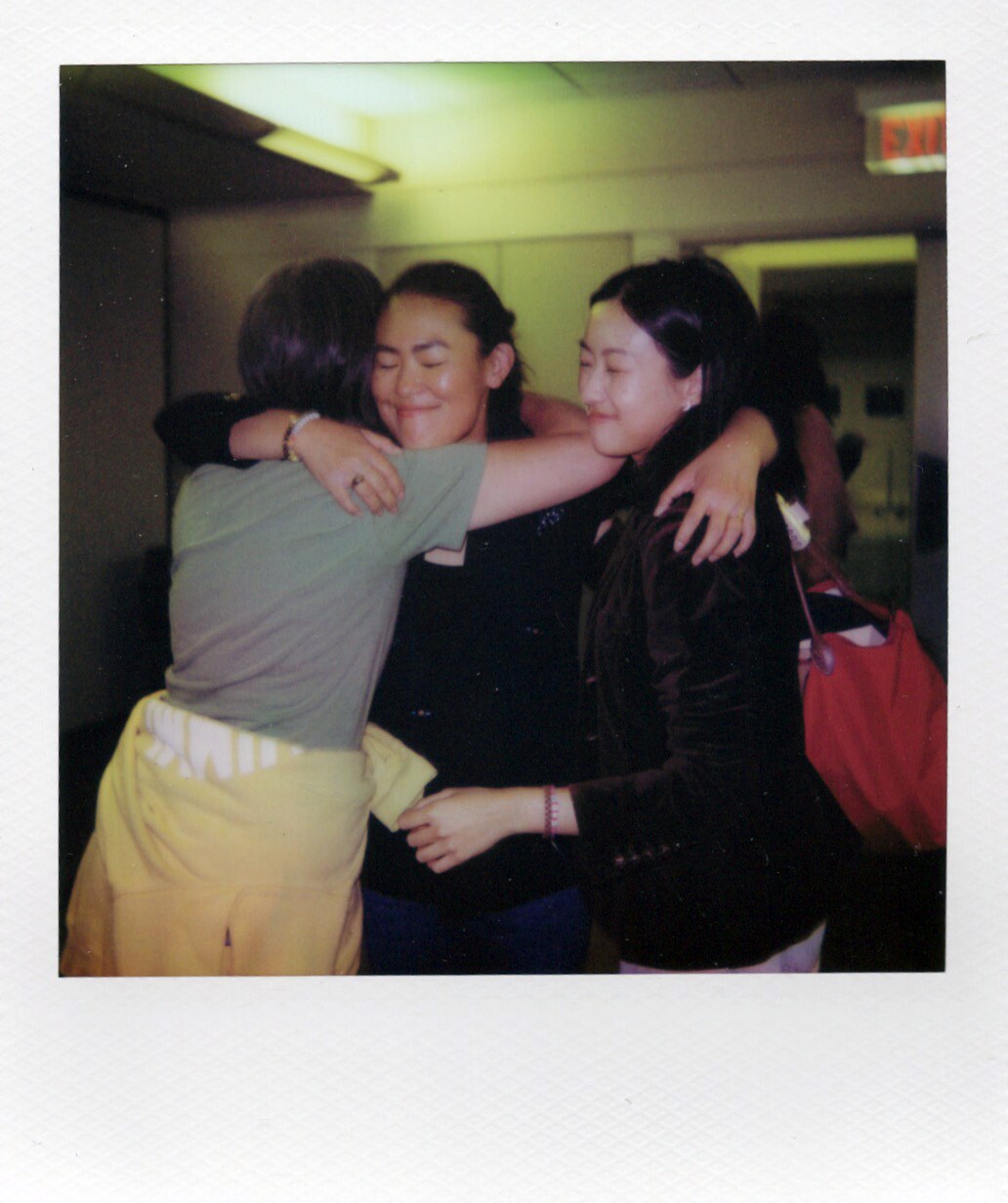 Three women hugging and laughing in a candid Book Talk Polaroid.