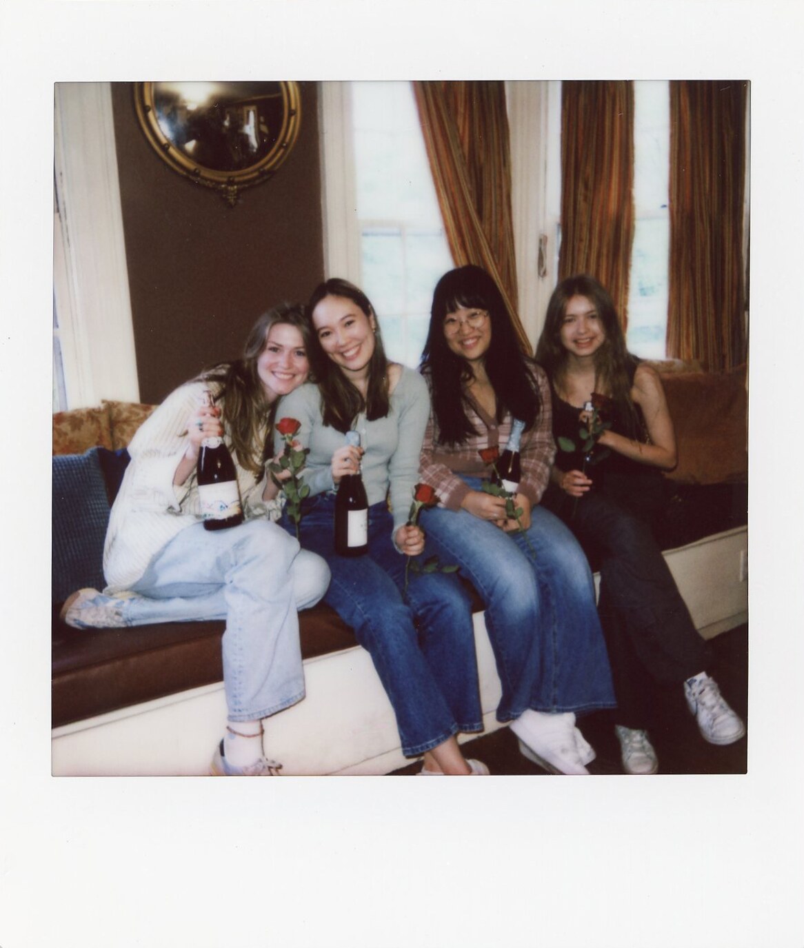 Four friends seated on a window seat in a Commencement Eve Polaroid.