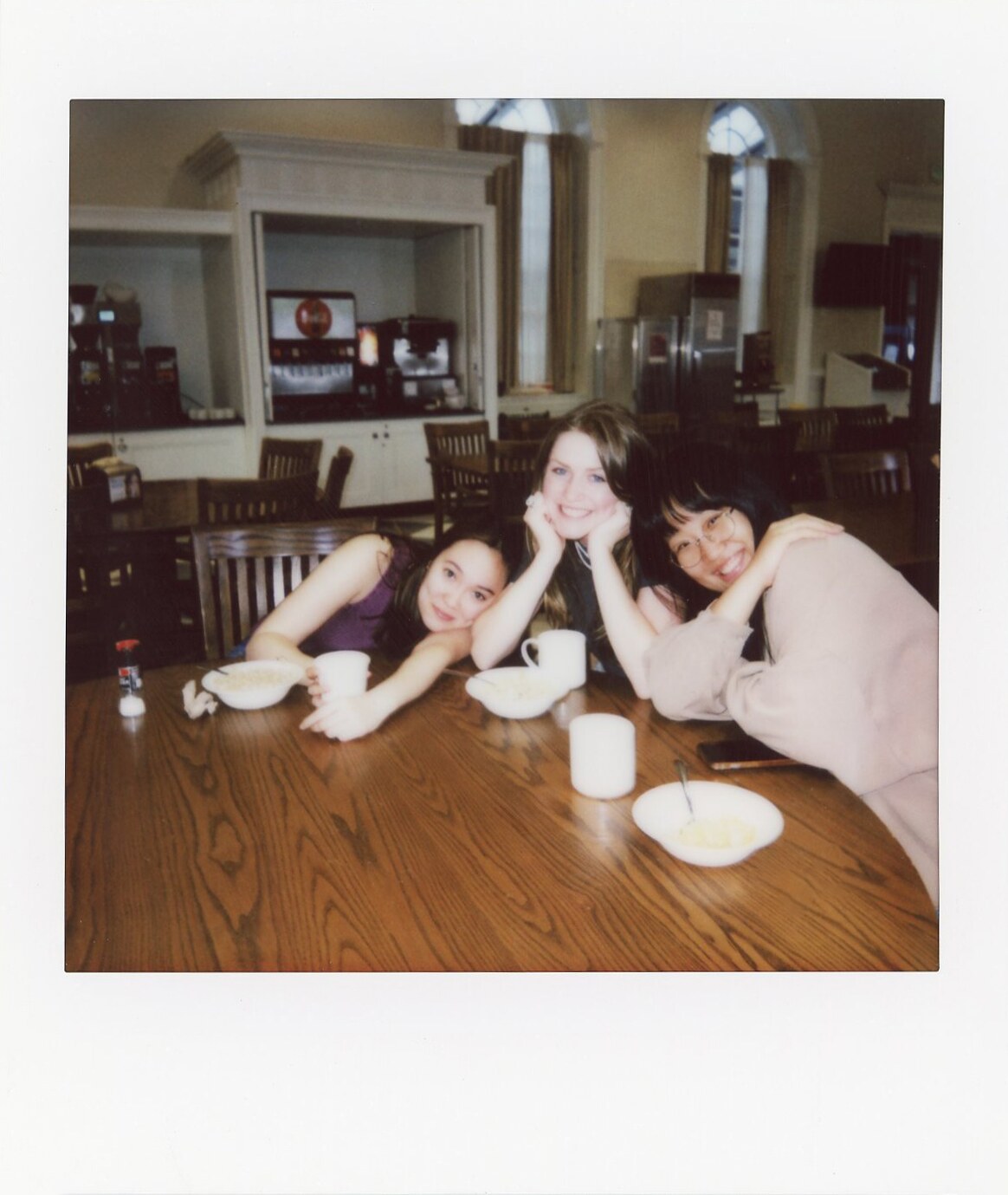 Four friends gathered around a table in a candid instant photograph.