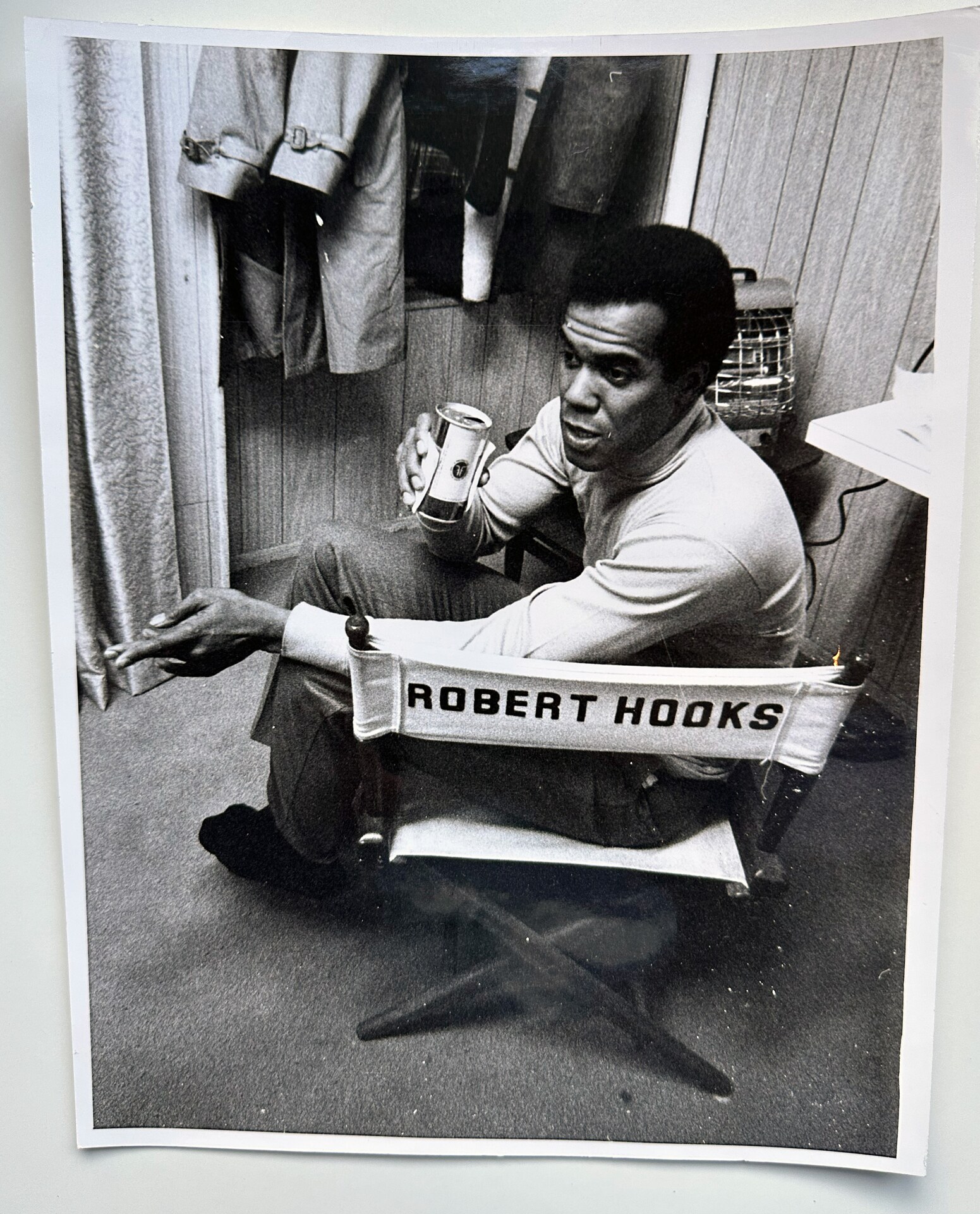 Black-and-white photograph of Robert Hooks seated beside a chair labeled Robert Hooks.