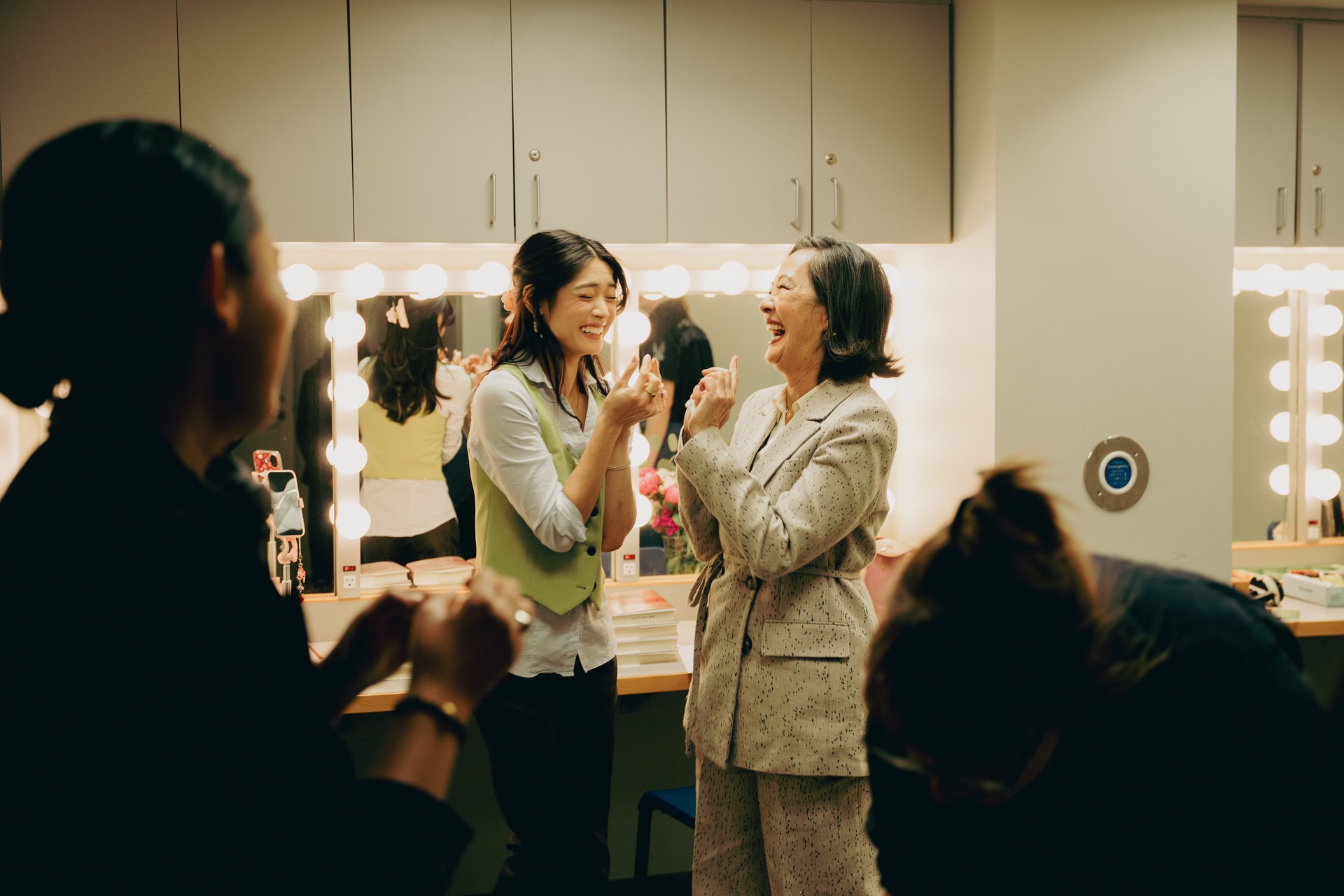 Two people talking in front of a dressing-room mirror.