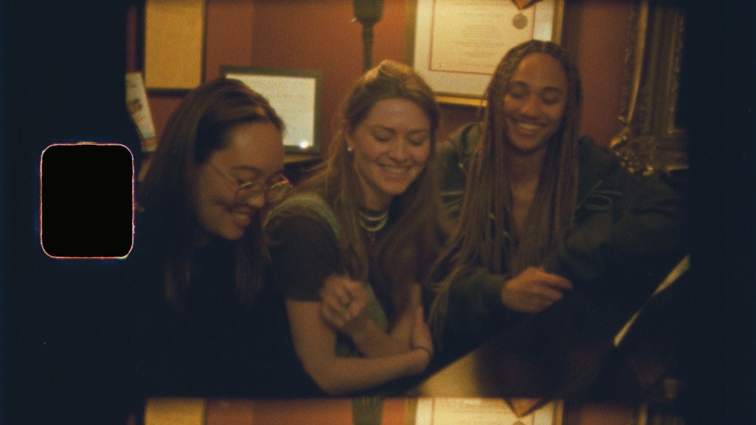 Three friends laughing together at a table.