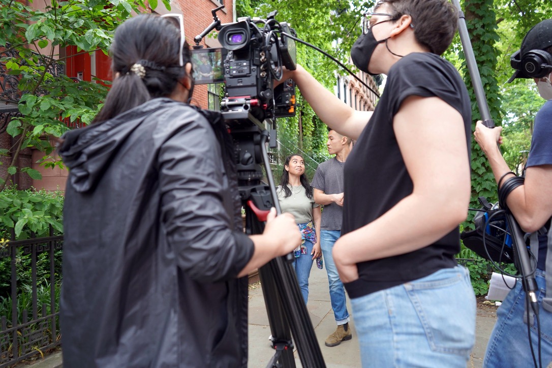 A camera crew filming outdoors in a garden.