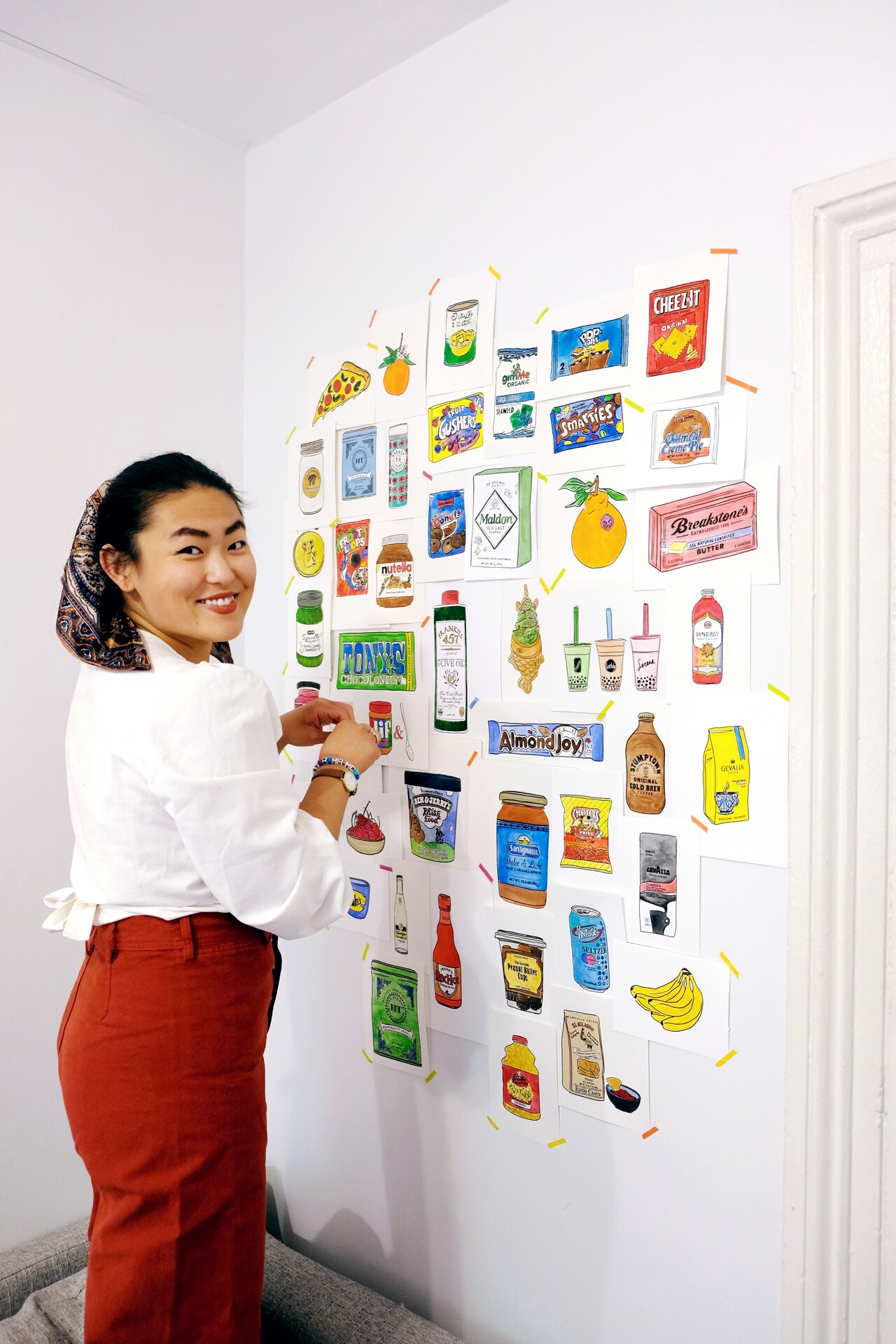 Grace standing beside a wall covered with colorful watercolor food illustrations.
